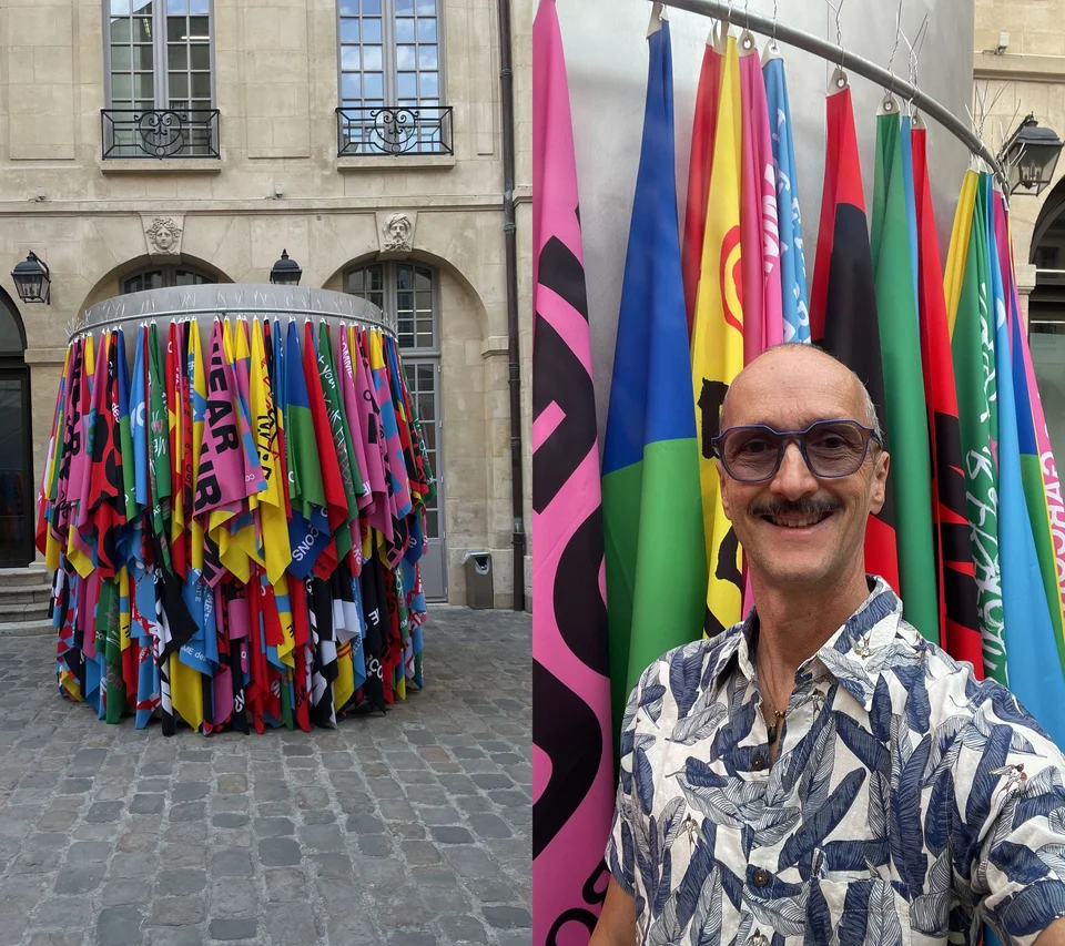 Il tourne son visage vers un arc-en-ciel de tissus, accrochés comme des rêves suspendus. Les couleurs dansent dans le vent, chantant des souvenirs d'été, de rires et de jeux.